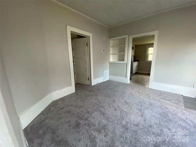 unfurnished bedroom with crown molding and dark carpet