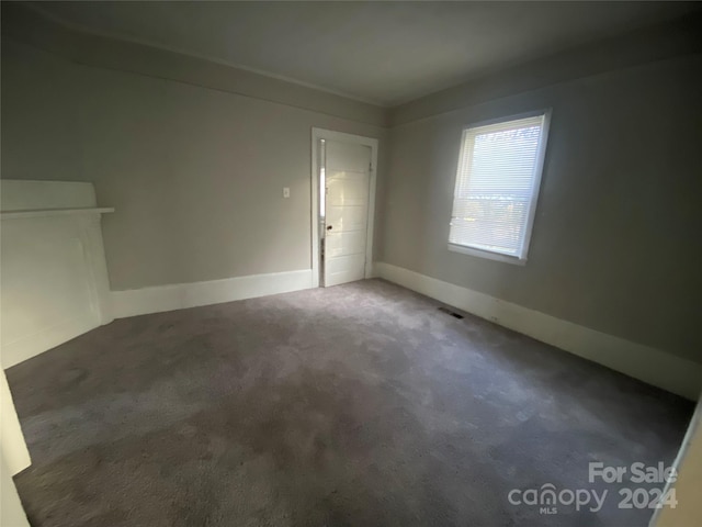 unfurnished room with dark colored carpet