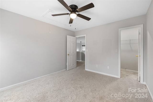 unfurnished bedroom featuring ceiling fan, a closet, light colored carpet, and a spacious closet