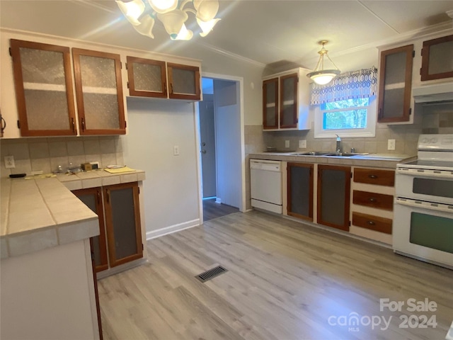 kitchen with pendant lighting, white appliances, backsplash, sink, and tile counters