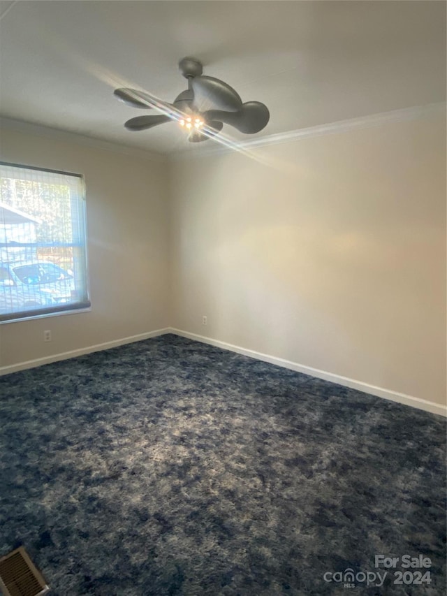 spare room with ceiling fan, dark carpet, and ornamental molding