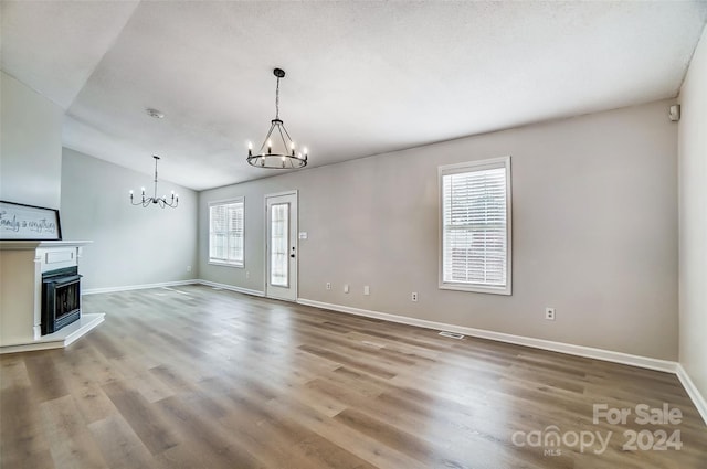 unfurnished living room featuring wood-type flooring, lofted ceiling, and a notable chandelier