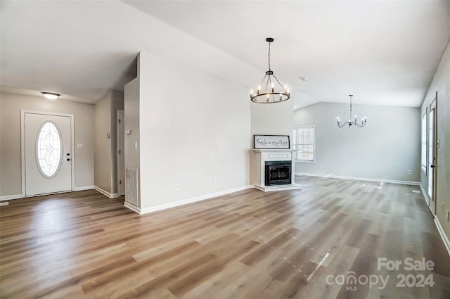 unfurnished living room featuring a chandelier, vaulted ceiling, and hardwood / wood-style flooring