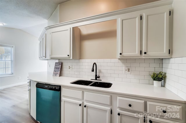 kitchen featuring backsplash, stainless steel dishwasher, a textured ceiling, sink, and lofted ceiling