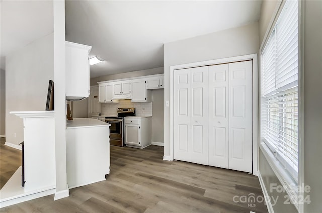 kitchen with backsplash, light hardwood / wood-style flooring, stainless steel electric range oven, and white cabinetry