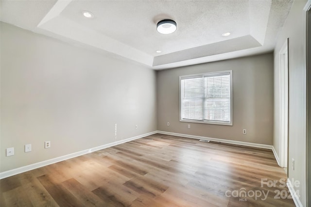 spare room featuring a raised ceiling and hardwood / wood-style flooring