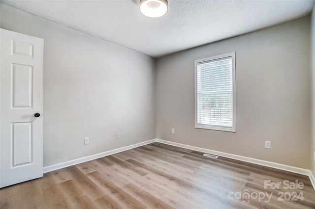 empty room featuring light hardwood / wood-style floors and a textured ceiling