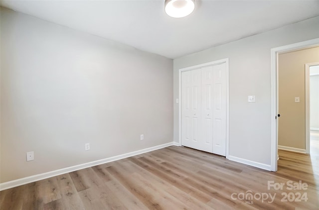 unfurnished bedroom featuring light hardwood / wood-style flooring and a closet