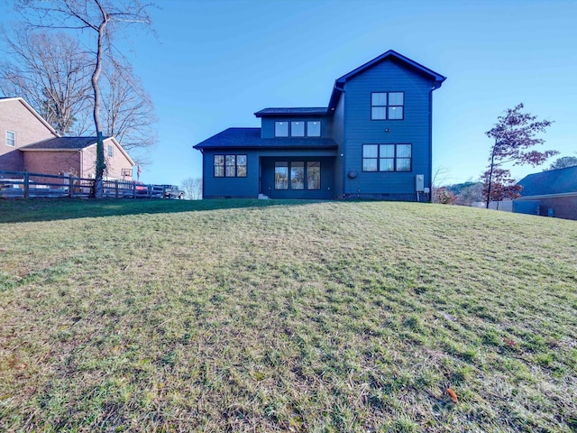 rear view of house featuring a yard and fence