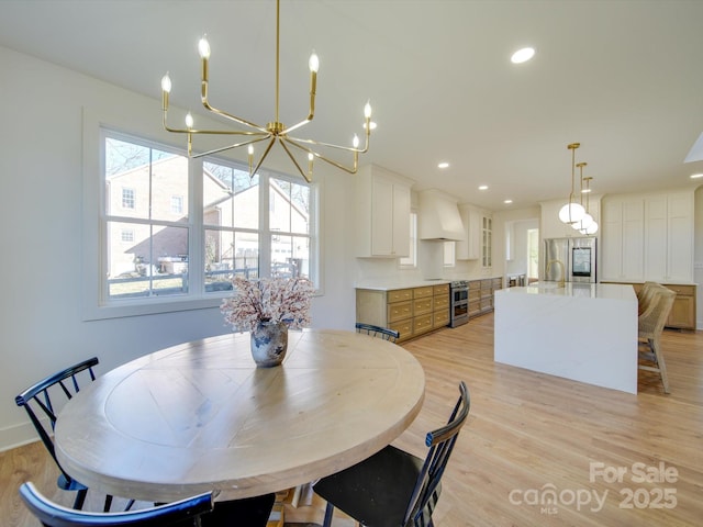 dining space with an inviting chandelier, sink, and light hardwood / wood-style flooring