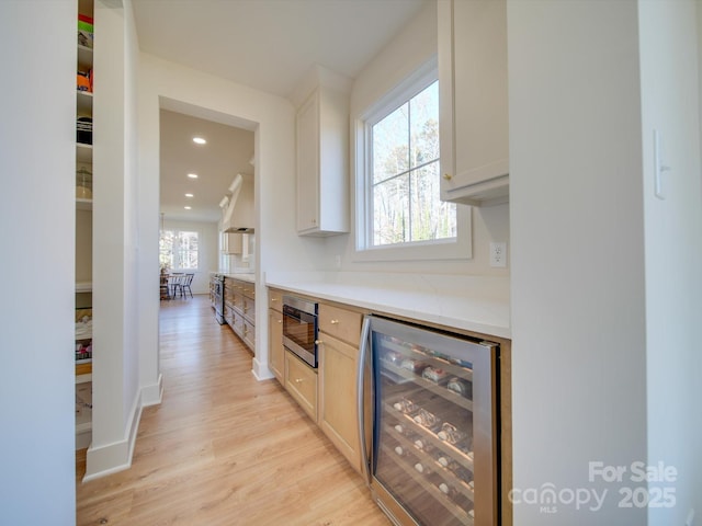 bar featuring light hardwood / wood-style floors, white cabinets, built in microwave, custom exhaust hood, and beverage cooler