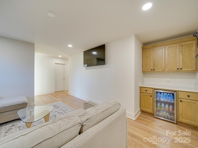 living room featuring bar, beverage cooler, and light hardwood / wood-style flooring