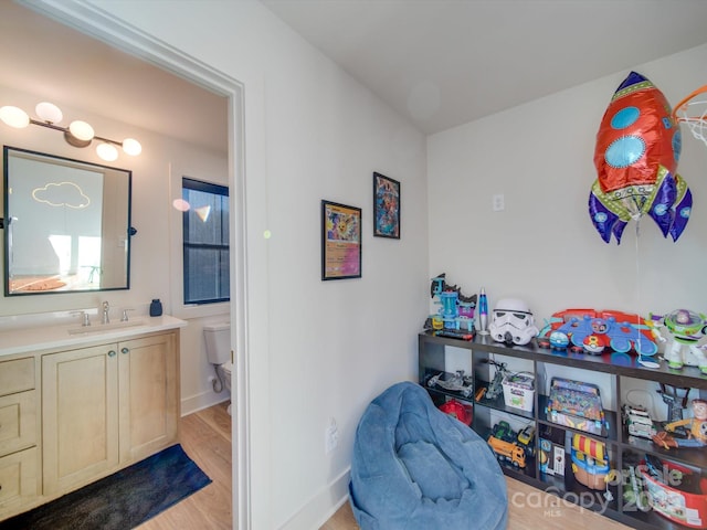 interior space with baseboards, toilet, wood finished floors, and vanity