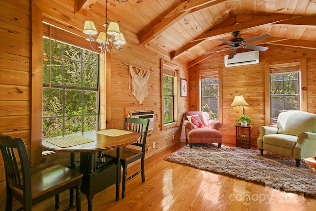 dining space featuring hardwood / wood-style flooring, wooden walls, a wall unit AC, and a wealth of natural light