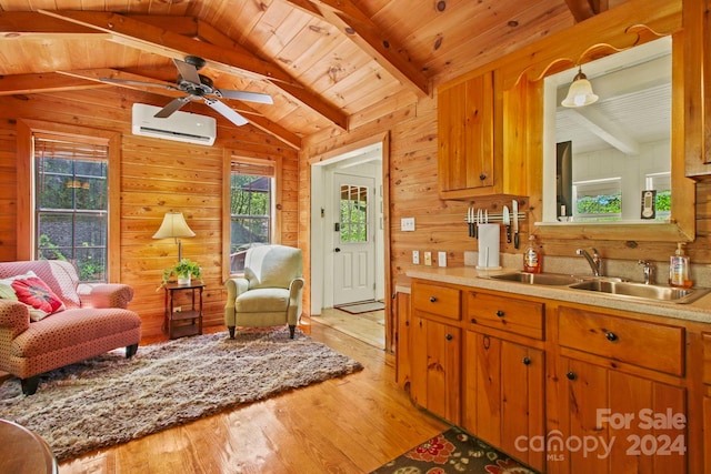 kitchen with a wall unit AC, wooden walls, sink, light hardwood / wood-style flooring, and vaulted ceiling with beams