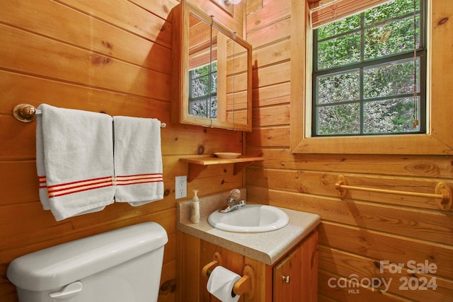 bathroom with a healthy amount of sunlight, toilet, and wooden walls