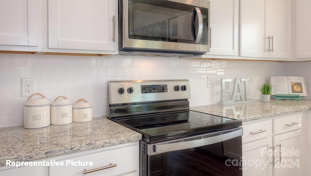 kitchen with white cabinets, appliances with stainless steel finishes, tasteful backsplash, and light stone counters