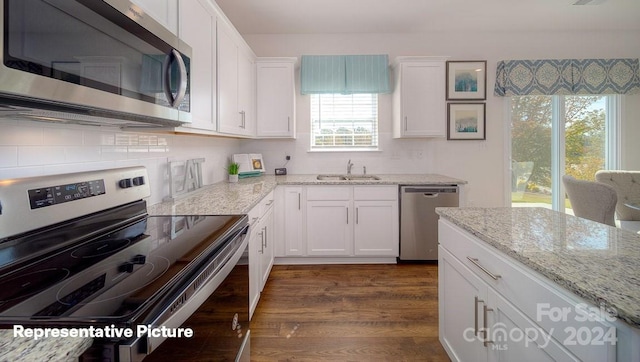 kitchen featuring sink, dark hardwood / wood-style floors, appliances with stainless steel finishes, light stone counters, and white cabinetry