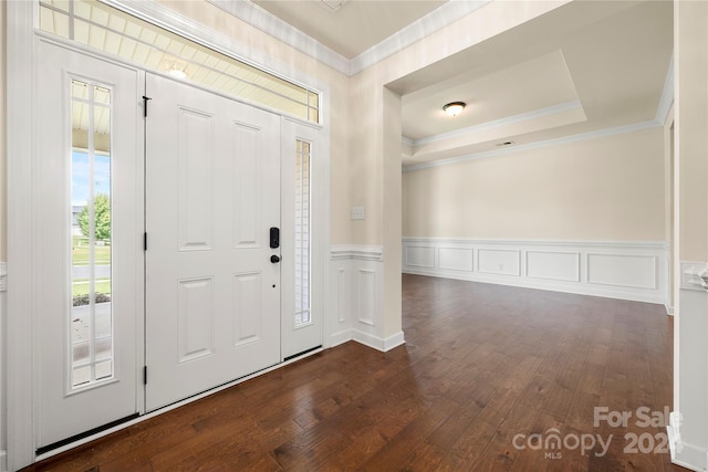 entryway with a raised ceiling, dark wood-type flooring, and crown molding