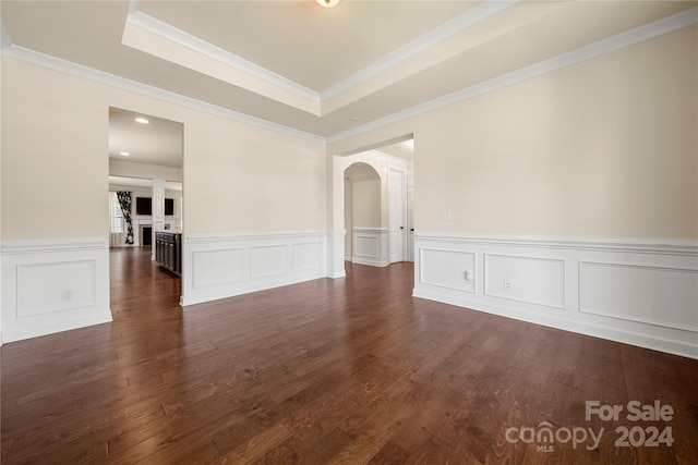 spare room with a raised ceiling, crown molding, and dark wood-type flooring