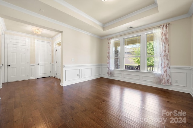 spare room featuring dark hardwood / wood-style flooring, ornamental molding, and a tray ceiling