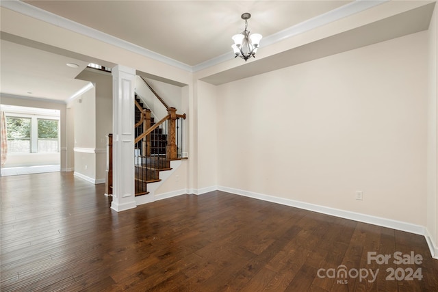 empty room featuring a notable chandelier, dark hardwood / wood-style floors, and ornamental molding