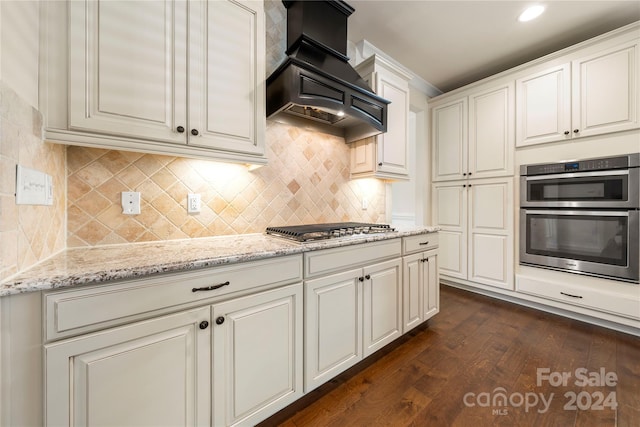 kitchen with light stone countertops, appliances with stainless steel finishes, premium range hood, and dark hardwood / wood-style floors