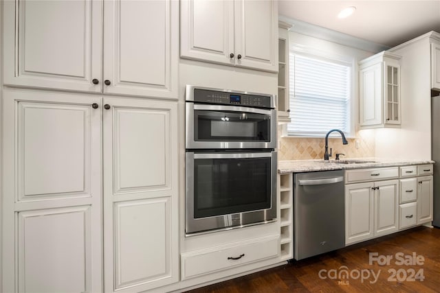 kitchen featuring appliances with stainless steel finishes, light stone counters, dark wood-type flooring, sink, and white cabinets