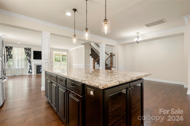 kitchen featuring dark brown cabinetry, dark wood-type flooring, a kitchen island, and ornate columns