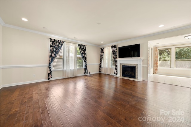 unfurnished living room with a high end fireplace, wood-type flooring, and ornamental molding