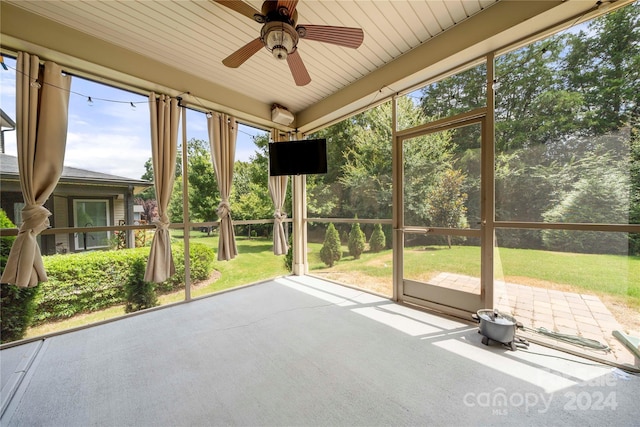 unfurnished sunroom featuring ceiling fan, a healthy amount of sunlight, and wood ceiling