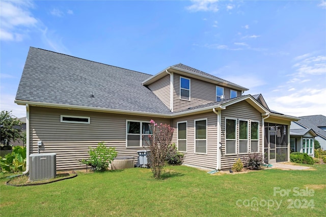 back of property featuring a lawn, a sunroom, and central AC