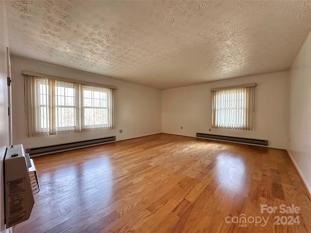 spare room with a textured ceiling, light hardwood / wood-style floors, and baseboard heating