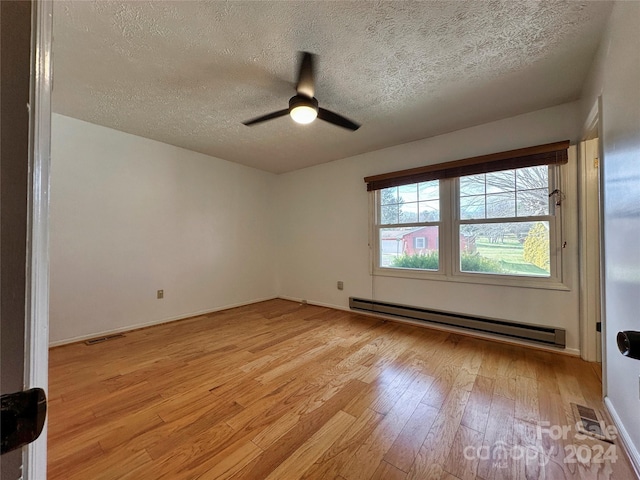 empty room featuring a textured ceiling, a baseboard radiator, light hardwood / wood-style flooring, and ceiling fan