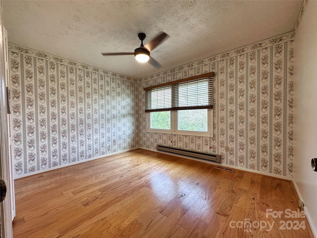 unfurnished room featuring a textured ceiling, ceiling fan, light wood-type flooring, and baseboard heating