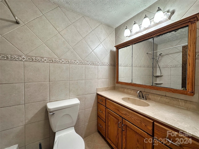 bathroom featuring vanity, a textured ceiling, toilet, and tile walls