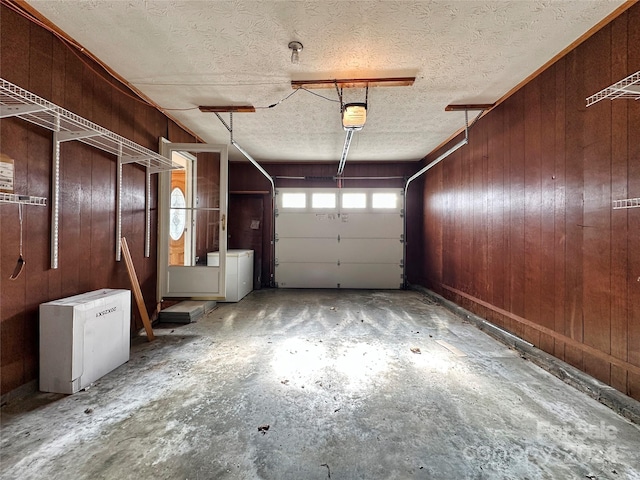 garage with washer and dryer, a garage door opener, fridge, and wooden walls