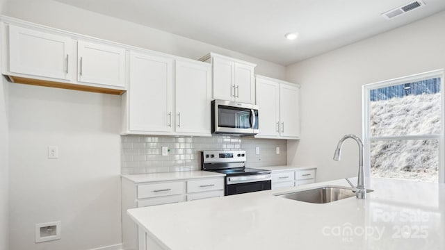 kitchen featuring a sink, visible vents, light countertops, appliances with stainless steel finishes, and decorative backsplash