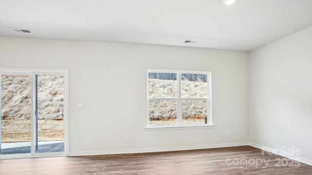 unfurnished room with wood finished floors, visible vents, and baseboards