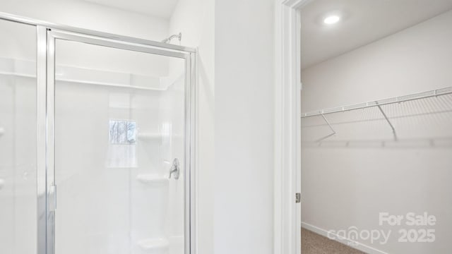 bathroom featuring a stall shower and a walk in closet