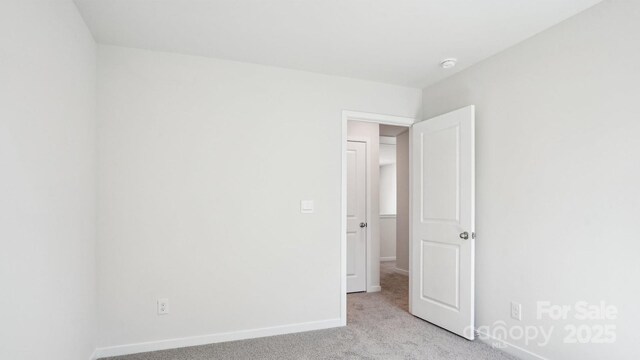 carpeted empty room featuring baseboards