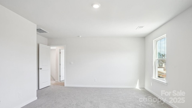 empty room featuring carpet flooring, visible vents, and baseboards