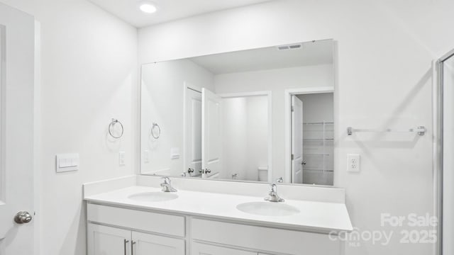 full bathroom with visible vents, a sink, toilet, and double vanity