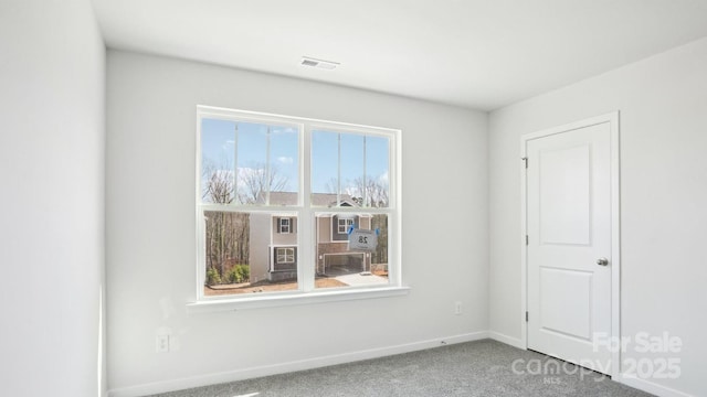 carpeted spare room with baseboards and visible vents