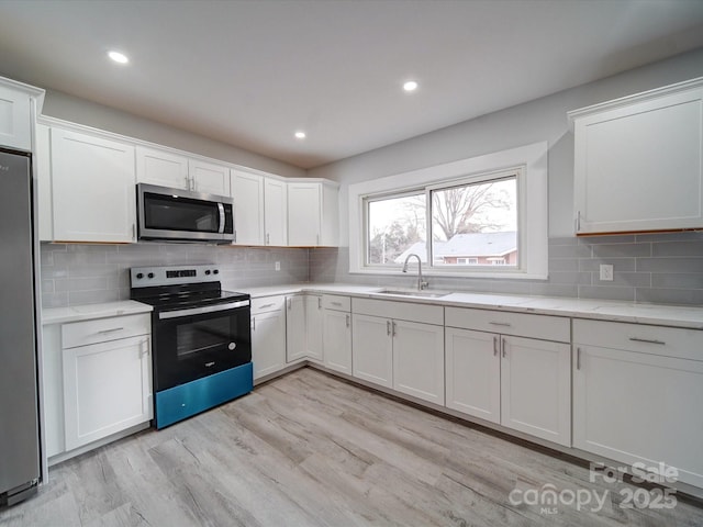 kitchen featuring stainless steel appliances, light hardwood / wood-style flooring, white cabinetry, and sink