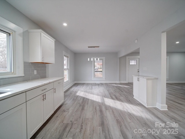 kitchen with pendant lighting, white cabinetry, tasteful backsplash, light hardwood / wood-style floors, and light stone counters