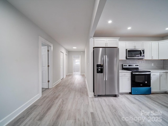 kitchen with light wood-type flooring, appliances with stainless steel finishes, decorative backsplash, and white cabinetry