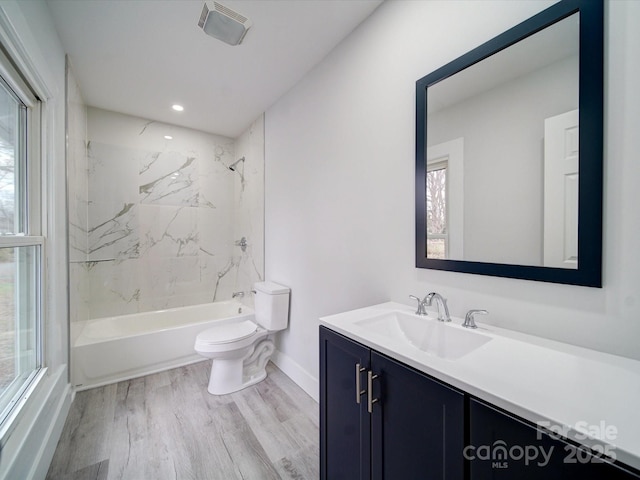 full bathroom featuring hardwood / wood-style floors, toilet, vanity, and tiled shower / bath combo