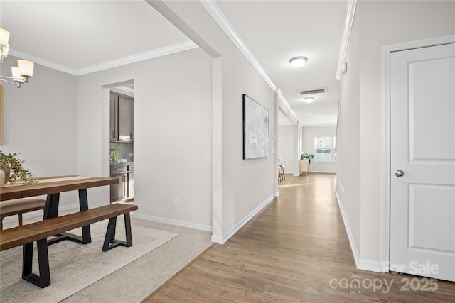 corridor with a chandelier, light hardwood / wood-style flooring, and crown molding