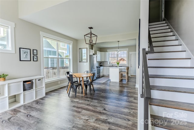 dining area featuring plenty of natural light, an inviting chandelier, and dark hardwood / wood-style floors